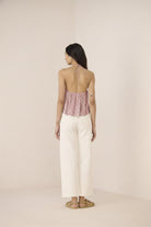 Woman wearing a patterned top and white pants on a beige background Calling June