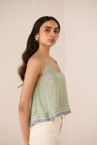 Woman wearing a green patterned top with a beige background Calling June