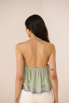 Woman wearing a green halter top with a beige background Calling June