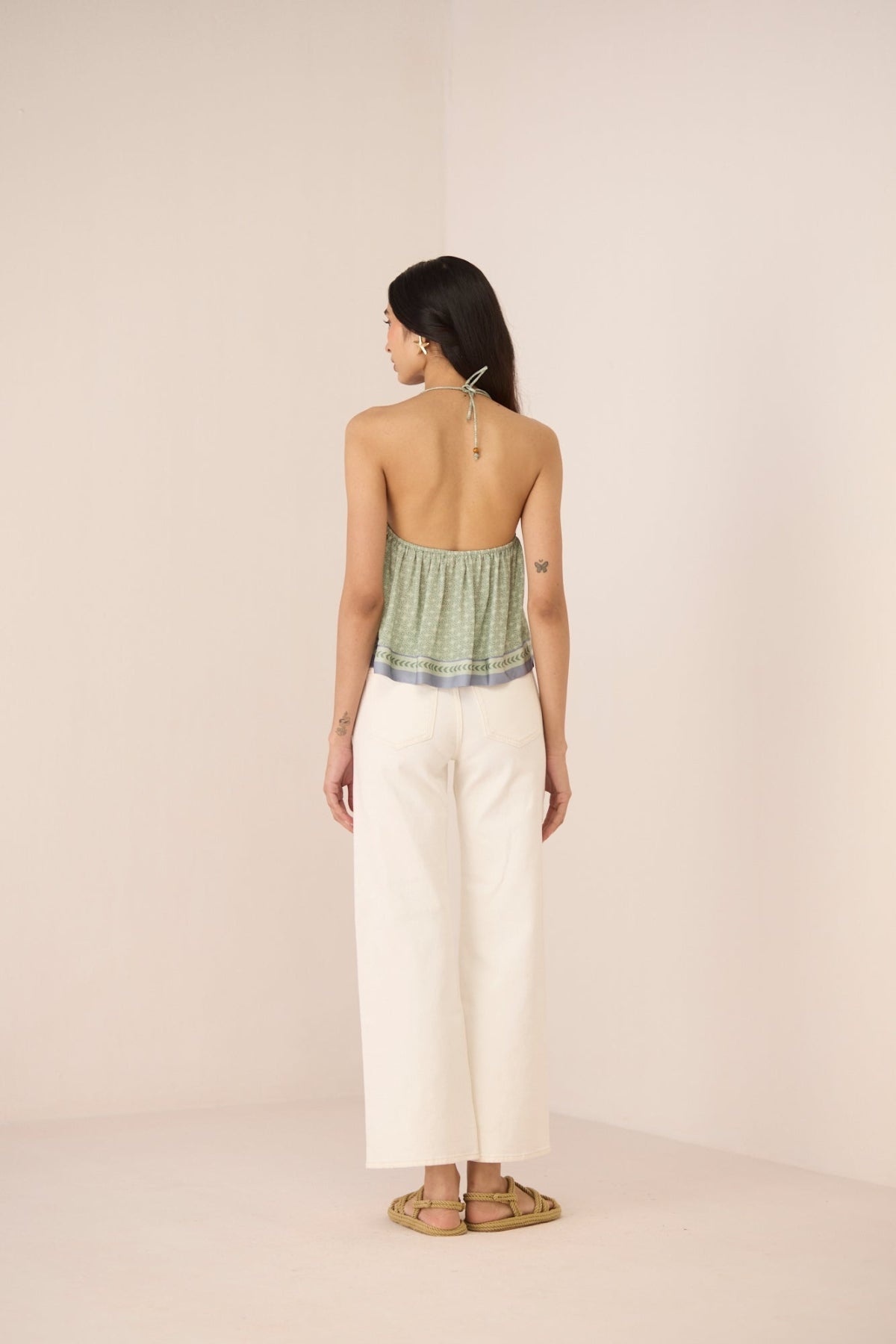 Woman wearing a green top and white pants on a beige background Calling June