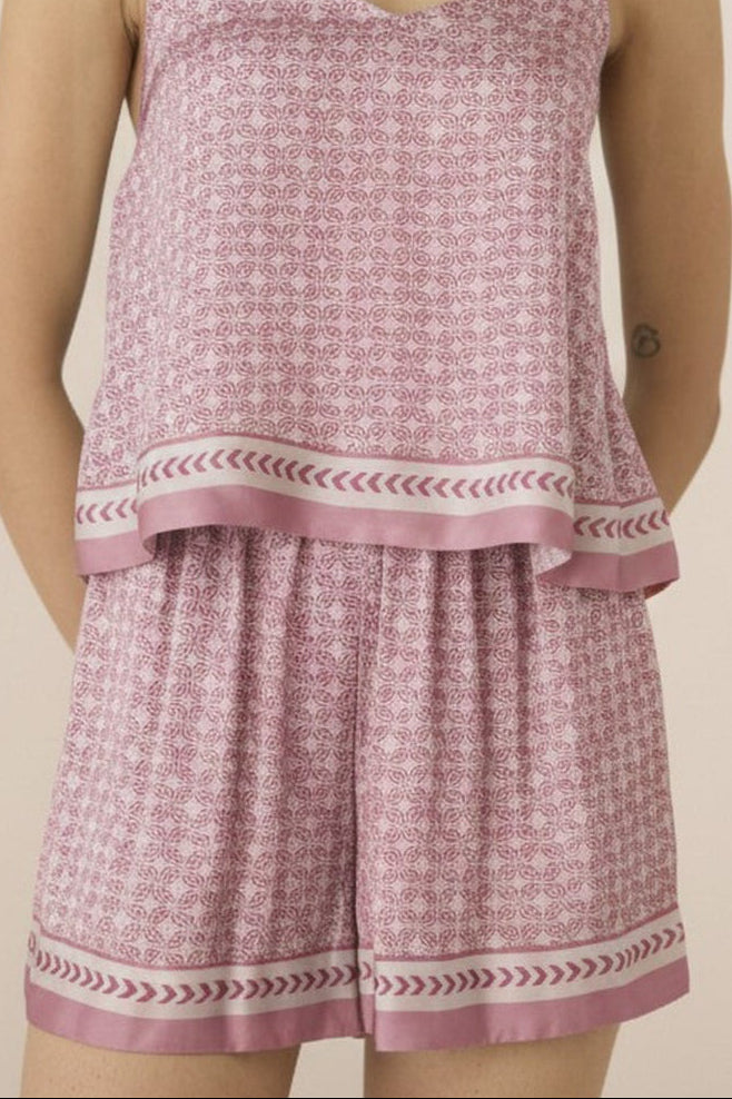 Woman wearing a pink checkered outfit with a plain background Calling June