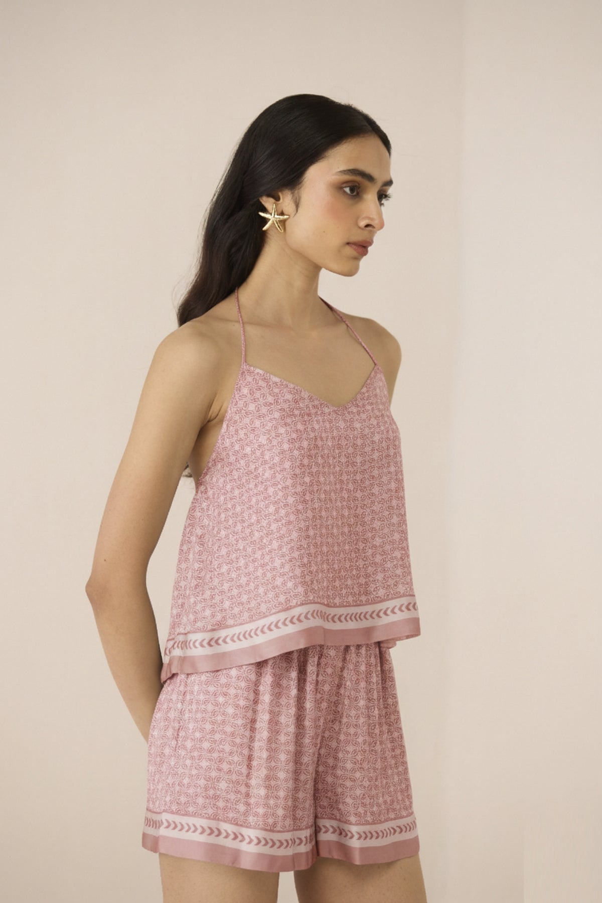 Woman wearing a pink checkered top and shorts set against a beige background Calling June