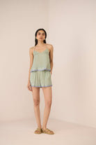 Woman wearing a light green patterned romper on a beige background Calling June