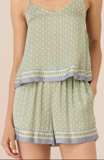 Woman wearing a light green patterned romper on a beige background Calling June