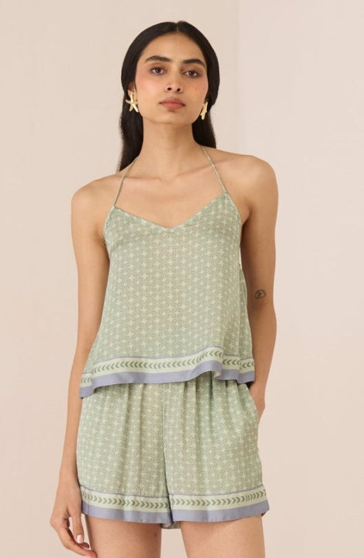Woman wearing a light green patterned romper on a beige background Calling June