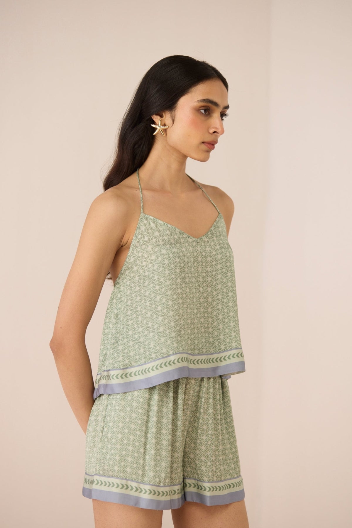 Woman wearing a light green sleeveless top and shorts set on a beige background Calling June