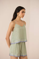 Woman wearing a light green sleeveless top and shorts set on a beige background Calling June