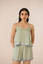 Woman wearing a green patterned top and shorts set on a beige background Calling June