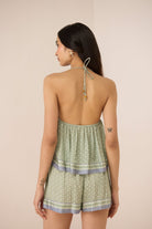 Woman wearing a green patterned romper with thin straps on a beige background Calling June