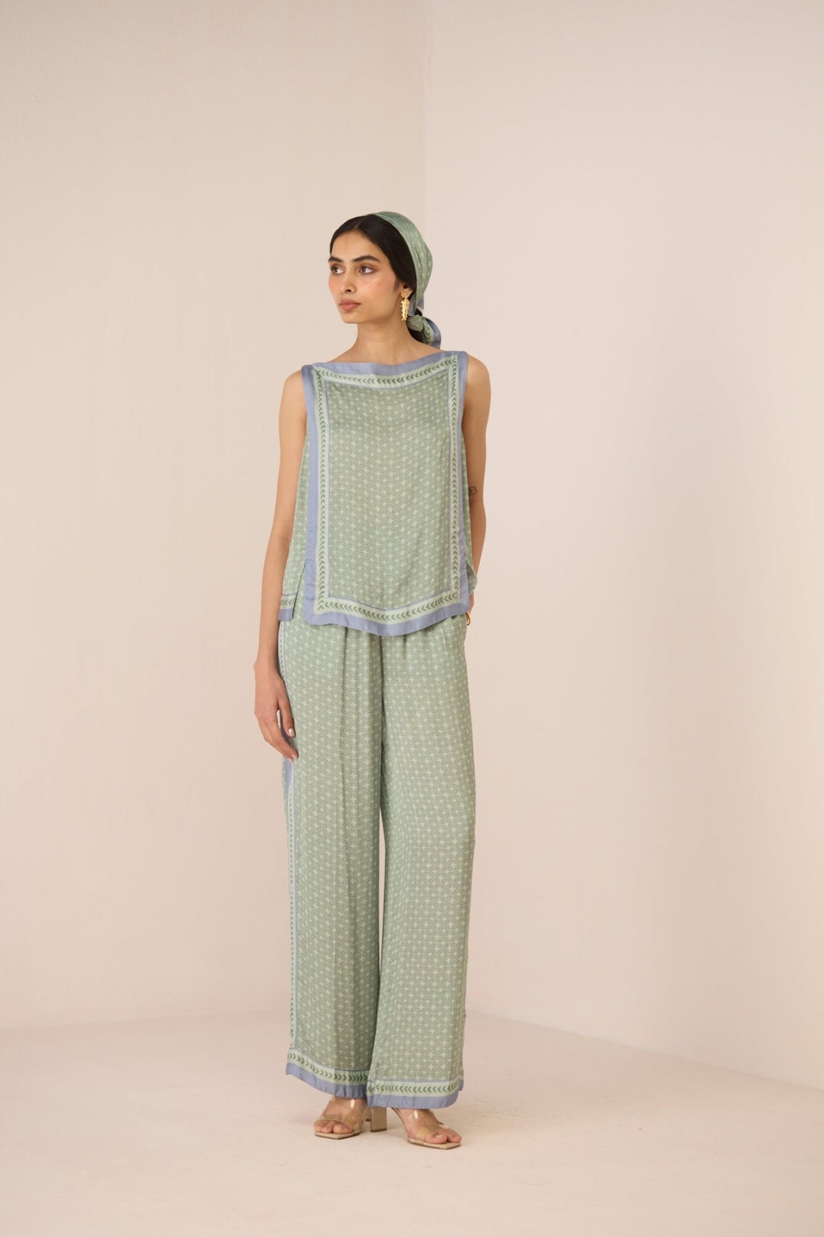 Woman wearing a green patterned outfit with a plain background Calling June