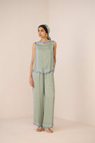 Woman wearing a green patterned outfit with a plain background Calling June