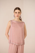 Woman wearing a pink patterned outfit against a beige background Calling June