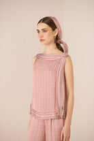 Woman wearing a pink patterned top and headscarf against a beige background Calling June