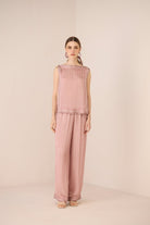 Woman wearing a pink textured sleeveless top and pants on a beige background Calling June