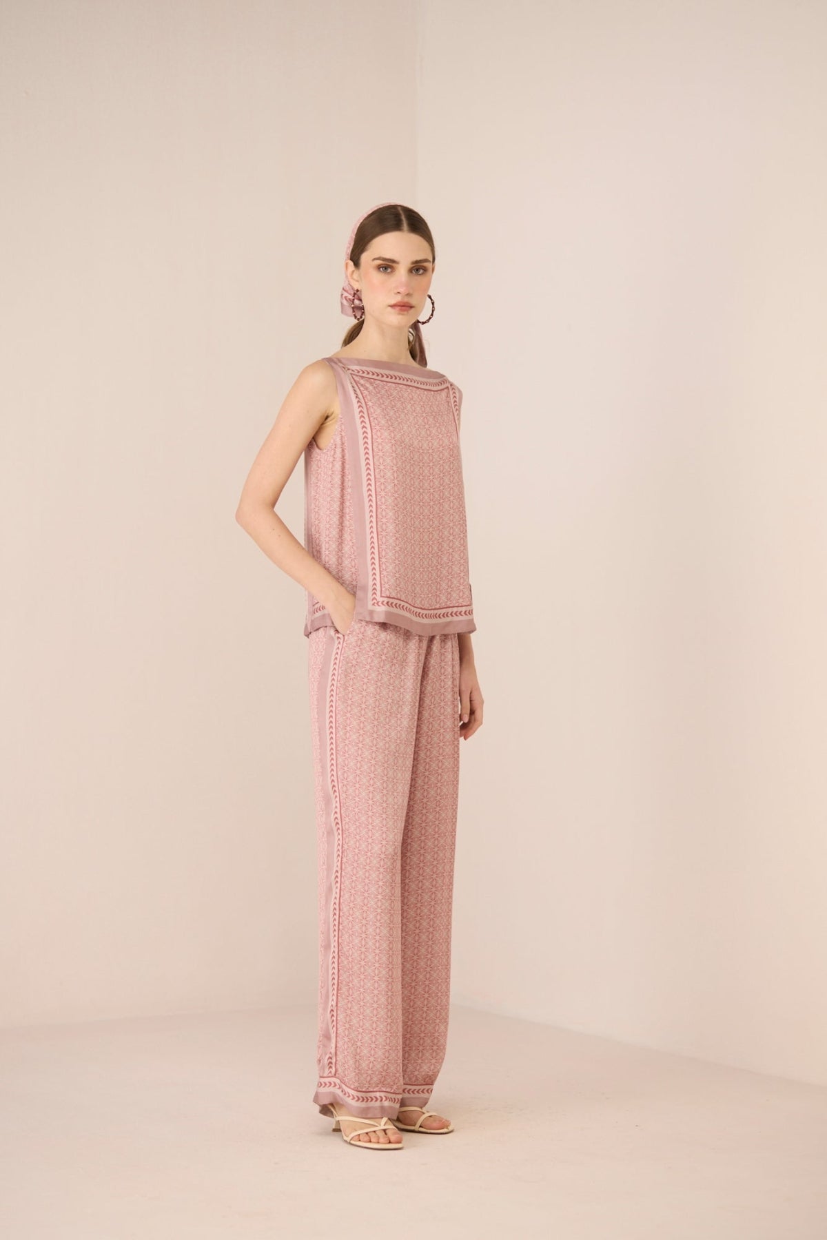 Woman wearing a pink textured outfit on a beige background Calling June