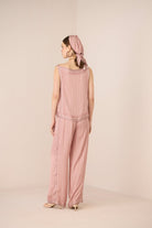Woman wearing a pink textured jumpsuit with a matching headscarf on a beige background Calling June