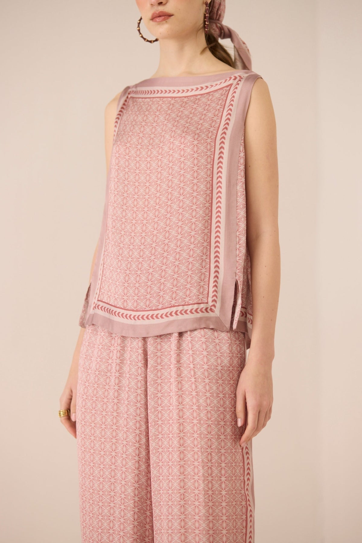 Woman wearing a pink patterned outfit on a beige background Calling June