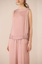 Woman wearing a pink patterned outfit on a beige background Calling June